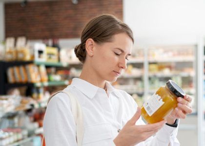 Donna che legge l’etichetta di un alimento al supermercato per conoscere ingredienti e valori nutrizionali, simbolo della crescente attenzione dei consumatori verso trasparenza e ingredienti funzionali nel food